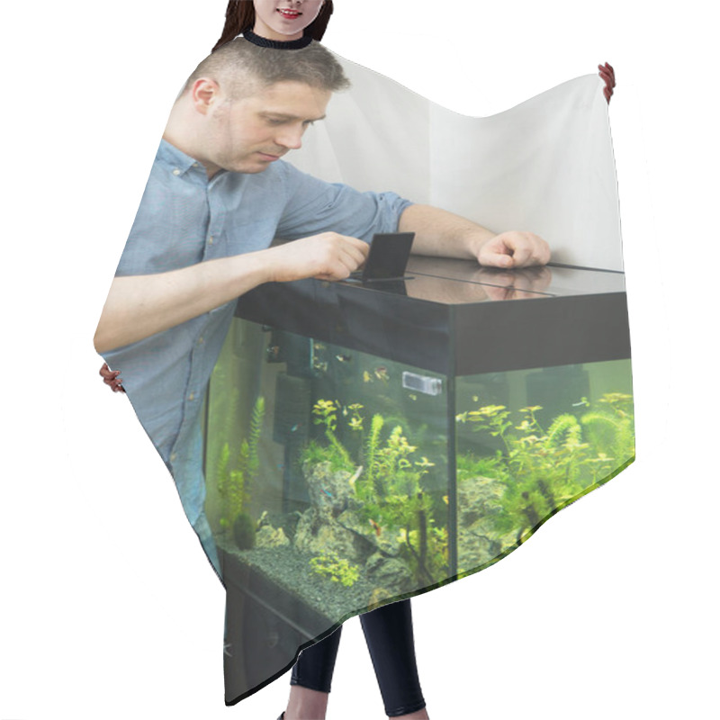 Personality  Handsome Man Feeding Fishes In The Aquarium. Hair Cutting Cape