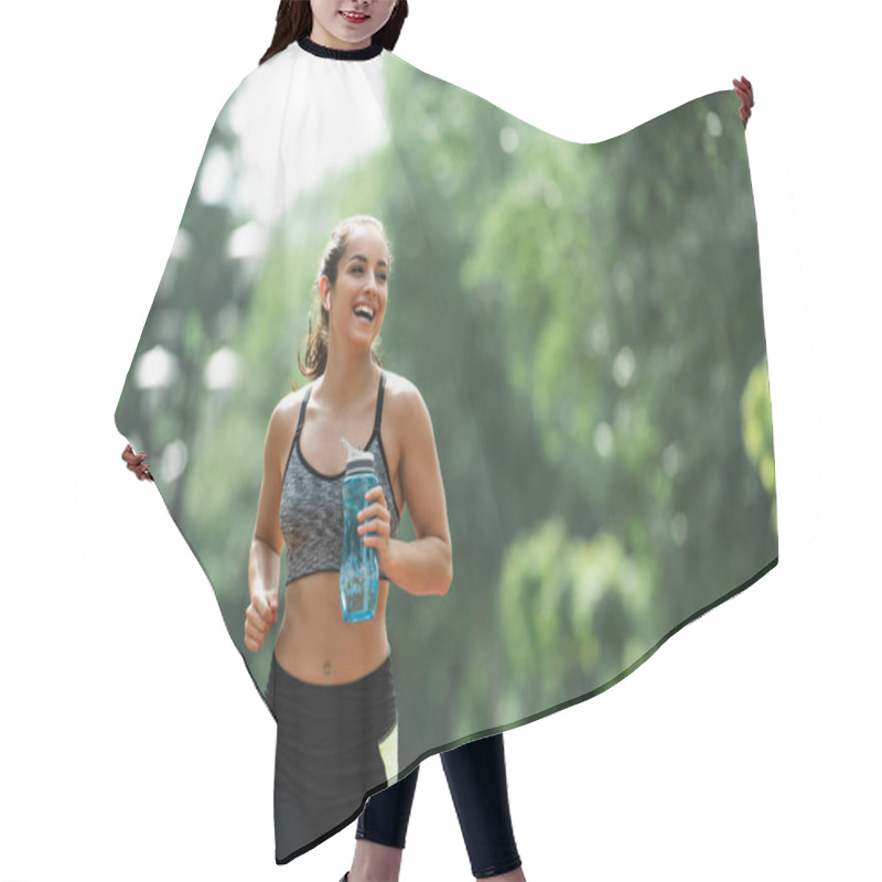 Personality  Cheerful Sportswoman In Wireless Earphones Holding Sports Bottle While Running In Green Park Hair Cutting Cape