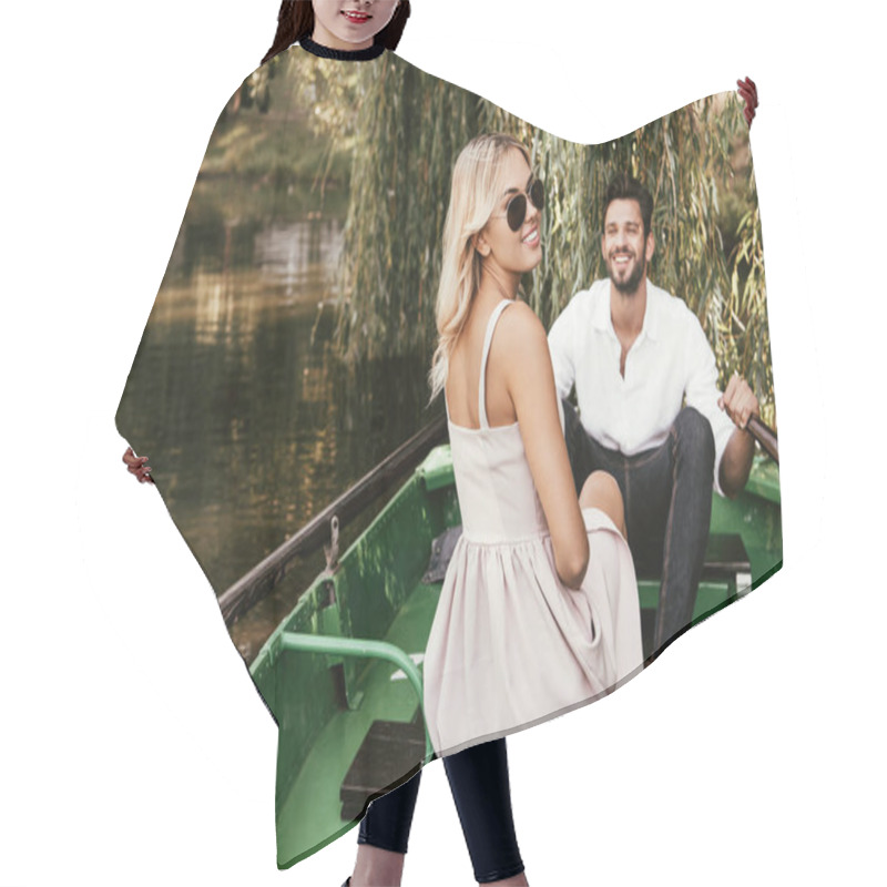 Personality  Cheerful Young Woman Looking At Camera While Sitting In Boat Near Happy Boyfriend Hair Cutting Cape