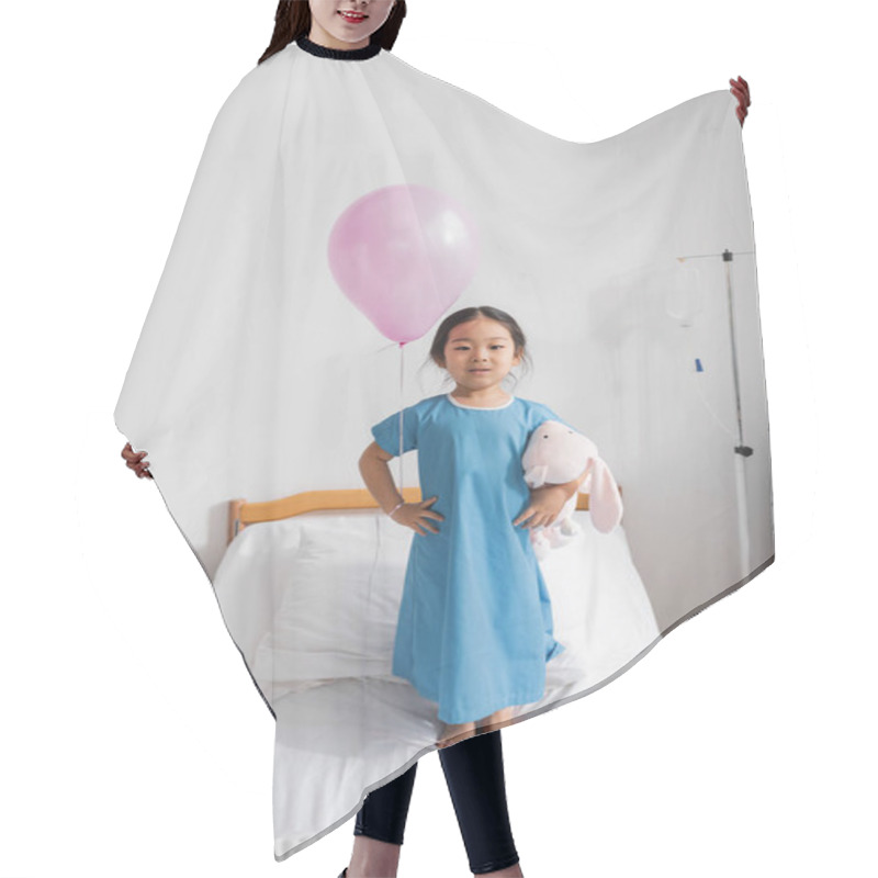 Personality  Full Length Of Asian Girl In Hospital Gown Standing With Toy Bunny And Festive Balloon On Bed In Pediatric Clinic Hair Cutting Cape