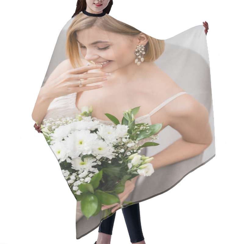 Personality  Special Occasion, Gorgeous Blonde Bride In Wedding Dress Sitting In Armchair And Holding Bouquet On Grey Background, Engagement Ring, White Flowers, Bridal Accessories, Happiness, Feminine  Hair Cutting Cape