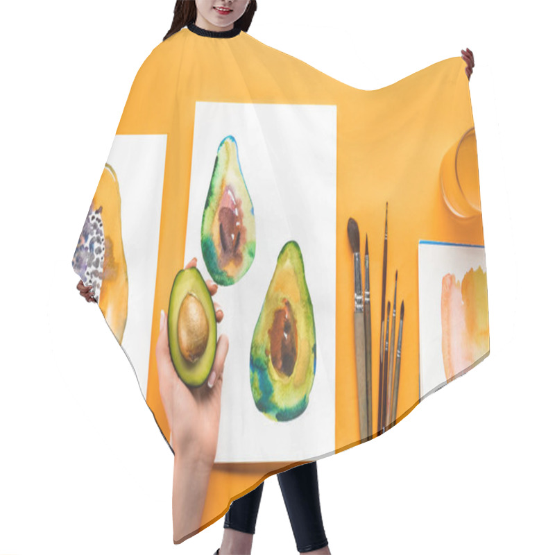 Personality  Top View Of Female Hand Holding Avocado Over Yellow Table With Drawings Of Fruits And Paintbrushes Hair Cutting Cape