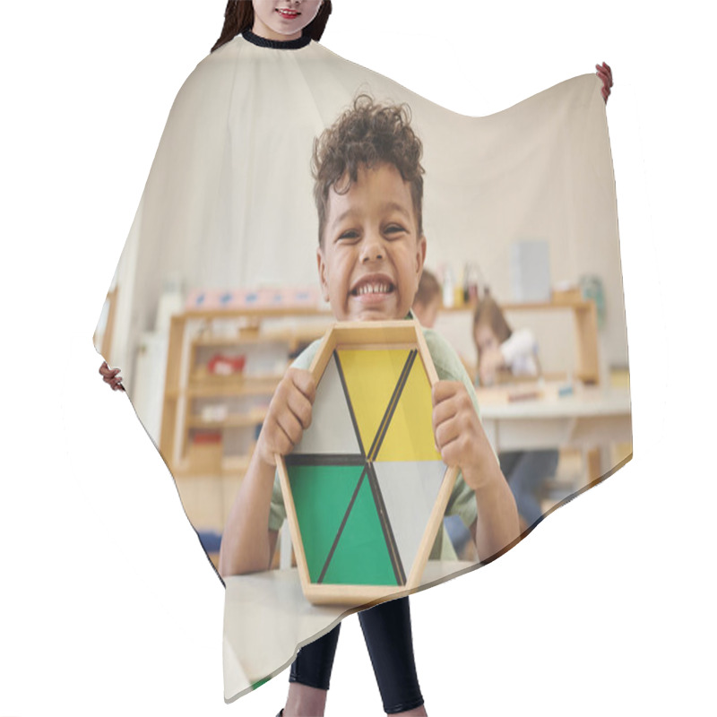 Personality  Positive African American Boy Holding Wooden Didactic Materials In Blurred Montessori School Hair Cutting Cape