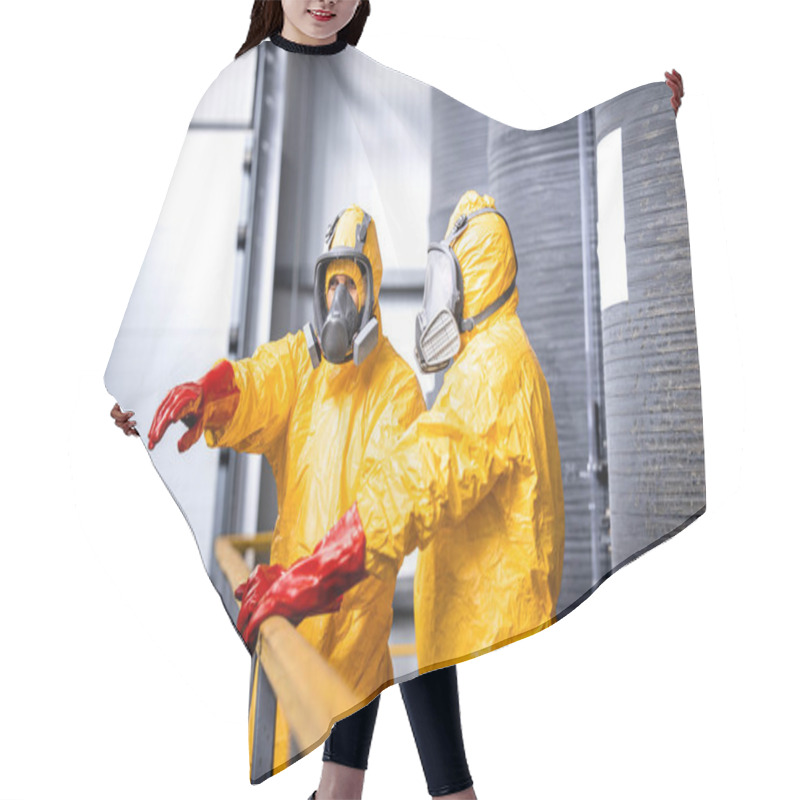 Personality  Factory Worker Standing By Large Metal Storage Tanks With Acids Wearing Yellow Protection Suit, Gas Mask And Gloves Explaining Trainee Process Of Chemicals Production Inside The Plant. Hair Cutting Cape