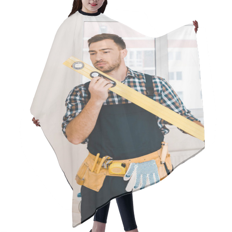 Personality  Handsome Handyman Looking At Measuring Level While Standing In Room Hair Cutting Cape