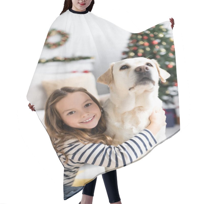 Personality  Girl Smiling At Camera While Hugging Labrador Near Blurred Christmas Tree At Home  Hair Cutting Cape