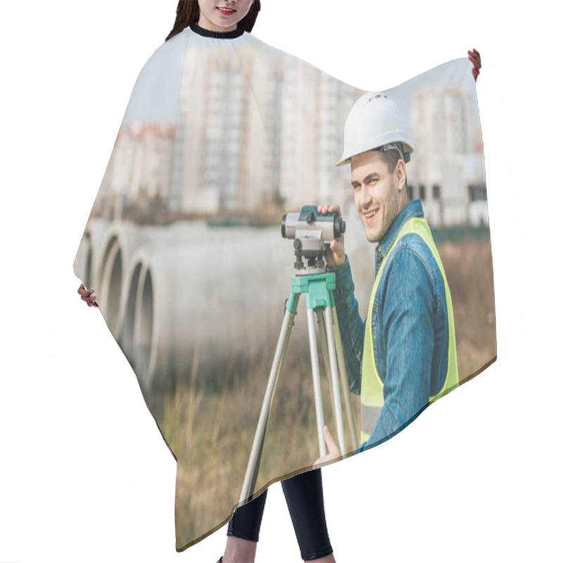 Personality  Surveyor With Digital Level Smiling At Camera With Building Materials At Background Hair Cutting Cape