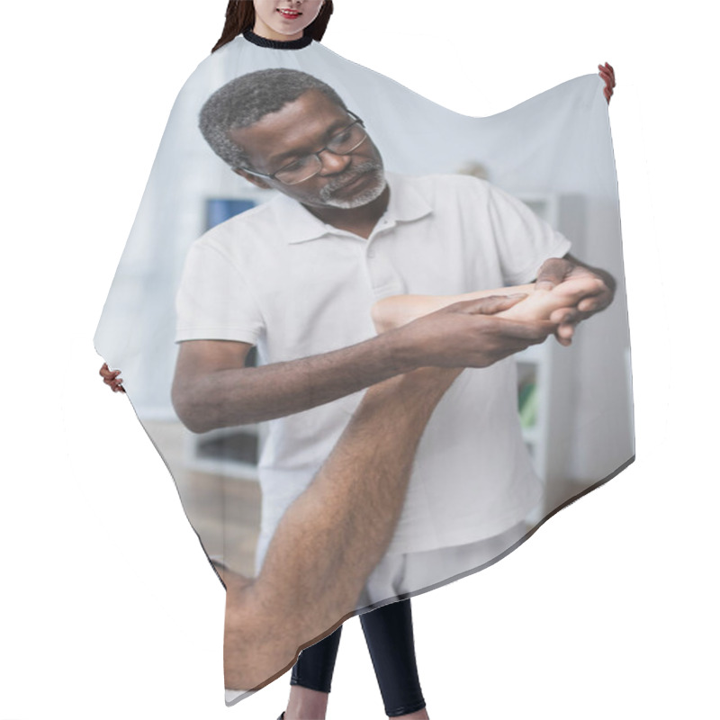 Personality  Middle Aged African American Physical Therapist Massaging Foot Of Man In Rehab Center Hair Cutting Cape