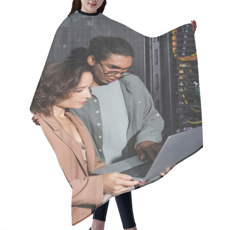 Personality  Couple Of Multiethnic Engineers Looking At Laptop While Checking Server In Data Center Hair Cutting Cape