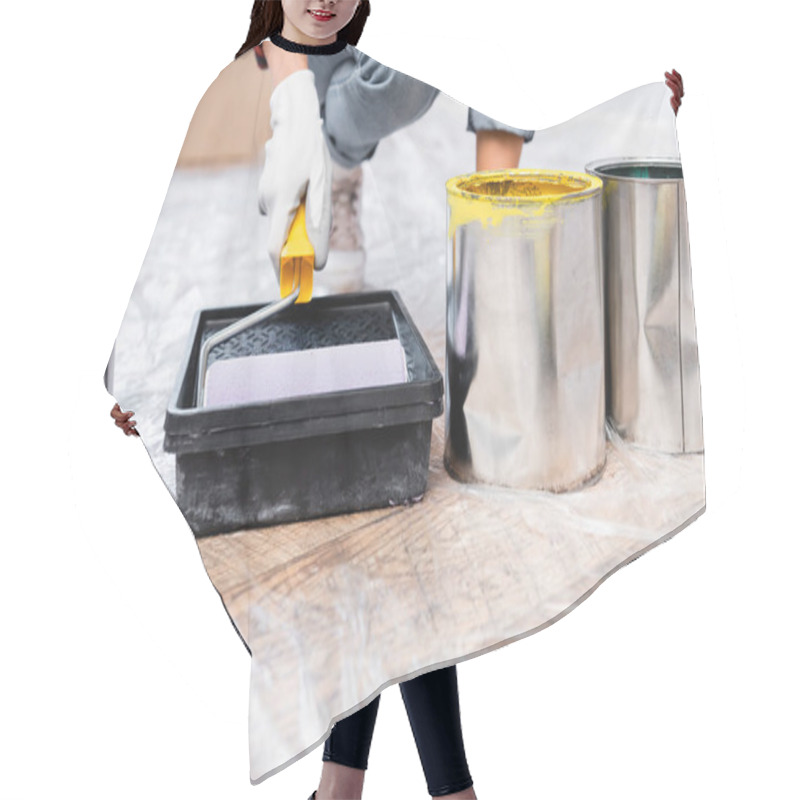 Personality  Cropped View Of Young Woman Holding Roller In Tray Near Tins Of Paint On Floor On Blurred Background Hair Cutting Cape