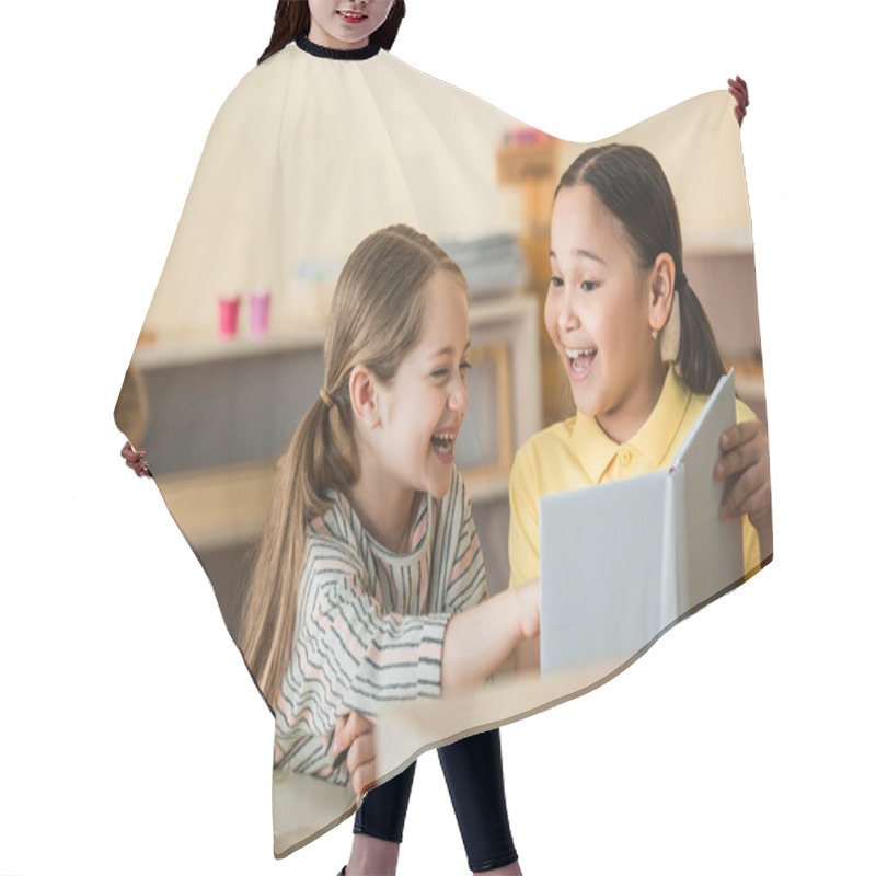 Personality  Excited Girl Pointing At Book Near Cheerful Asian Friend In Montessori School Hair Cutting Cape