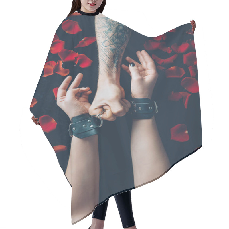 Personality  Cropped Shot Of Man Holding Handcuffs On Female Hands Above Black Fabric With Red Rose Petals Hair Cutting Cape