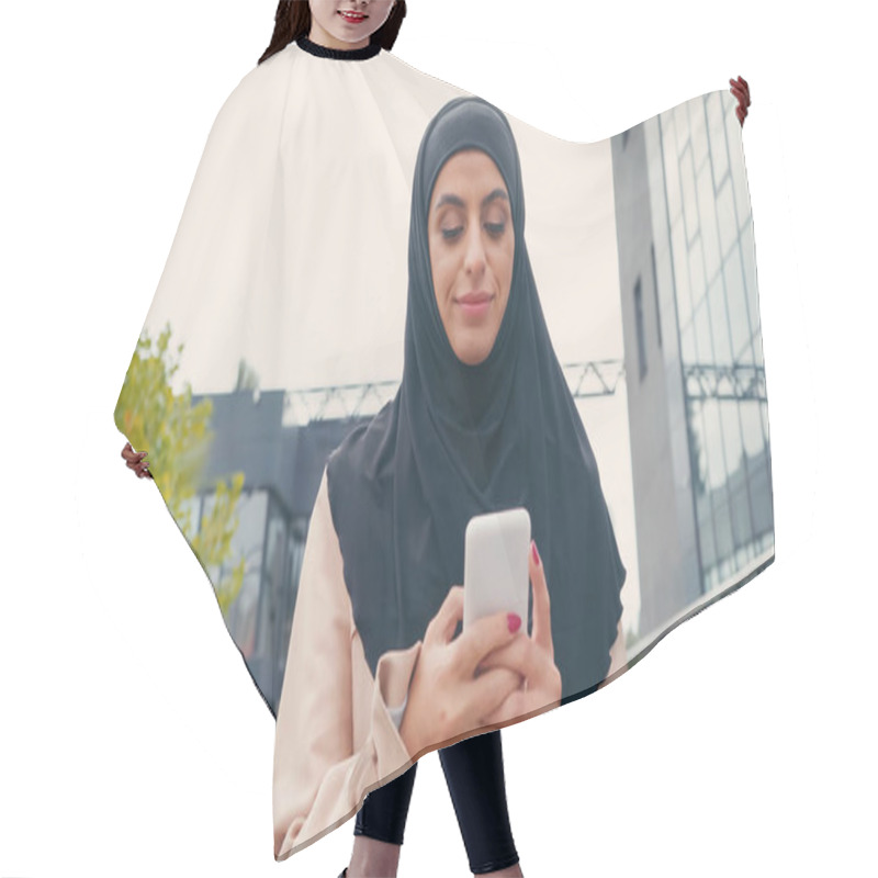 Personality  Young Muslim Woman In Hijab Messaging On Smartphone Outside Hair Cutting Cape