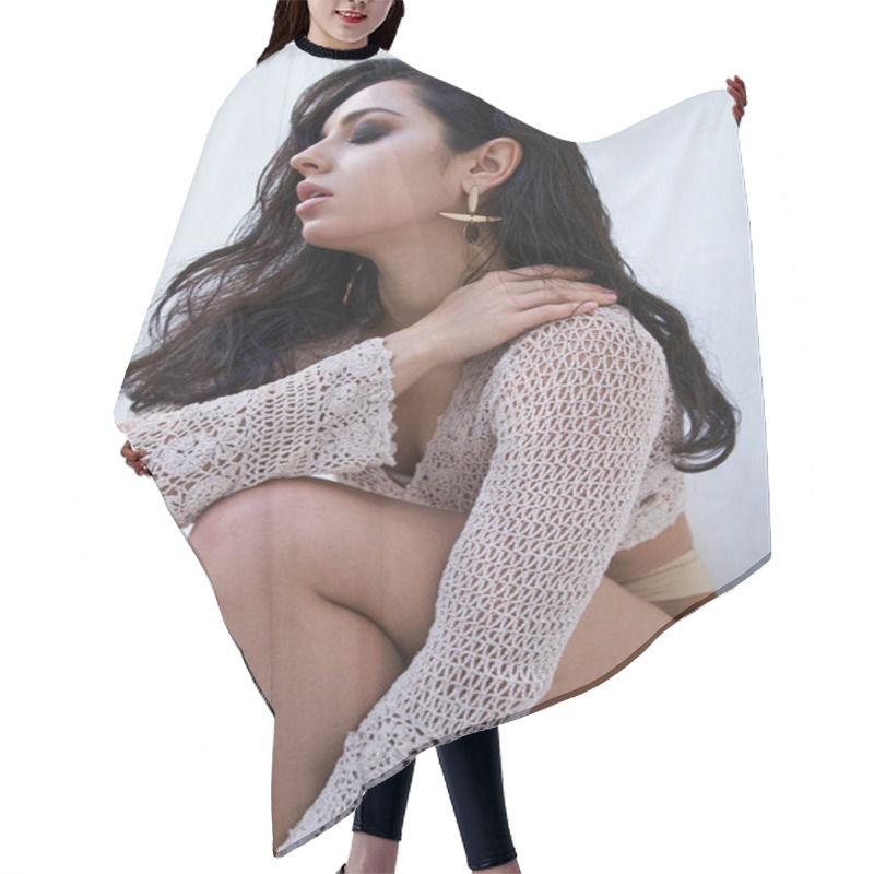 Personality  A Young Woman With Long Brunette Hair Poses In A White Knitted Top Against A White Backdrop. Hair Cutting Cape