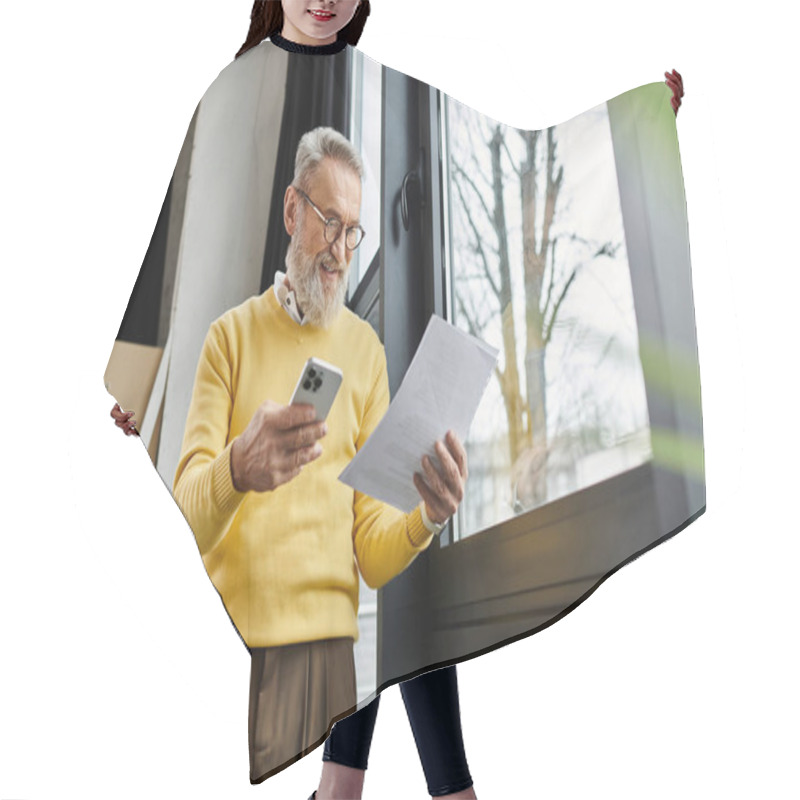 Personality  Senior Man In A Yellow Sweater Reviews Documents While Checking His Smartphone. Hair Cutting Cape