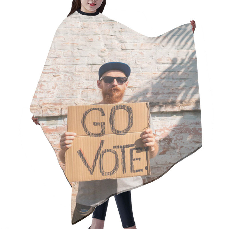 Personality  Man Shows Cardboard With Go Vote Sign On Brick Wall Urban Background. Voting Concept. Make The Political Choice, Use Your Voice. Bearded Guy In Sunglasses Invite To Go To The Presidential Elections. Hair Cutting Cape