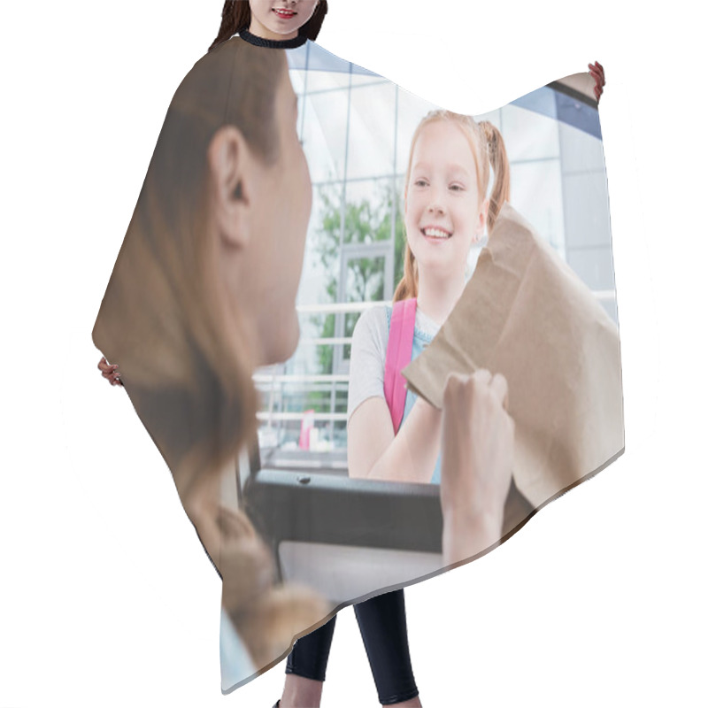 Personality  Selective Focus Of Woman In Car Giving Paper Package With Food To Smiling Daughter Hair Cutting Cape