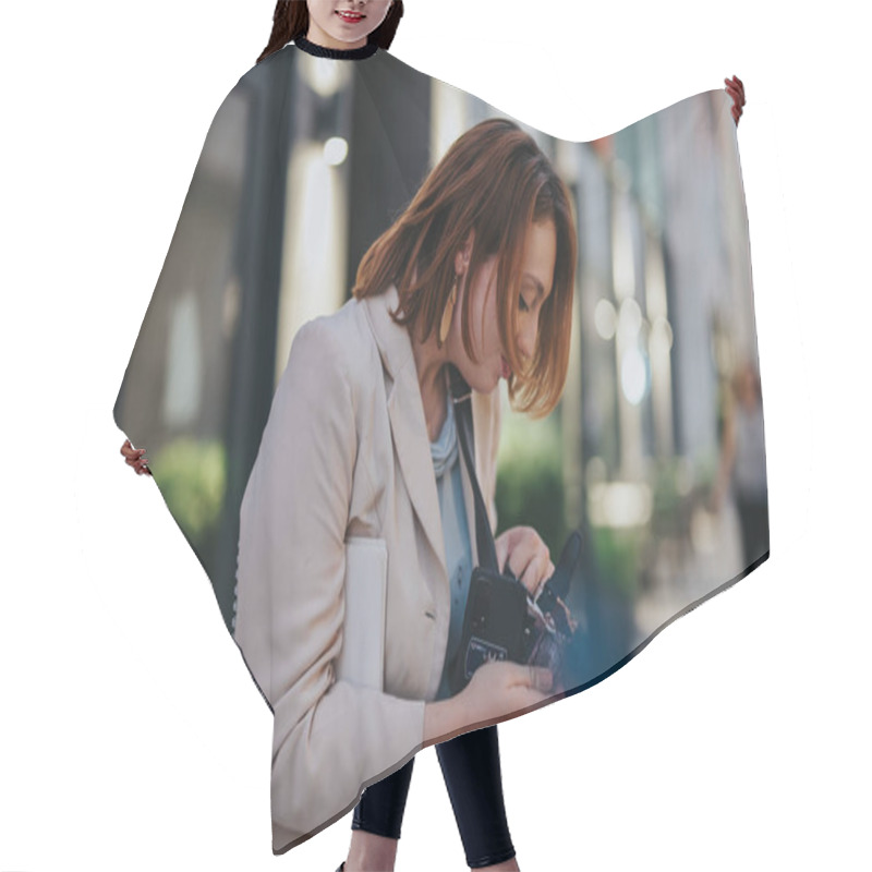 Personality  A Professional Woman Examines A Camera On A Busy City Street, Dressed In A Smart Blazer, Highlighting Urban Lifestyle And Modern Technology. Hair Cutting Cape