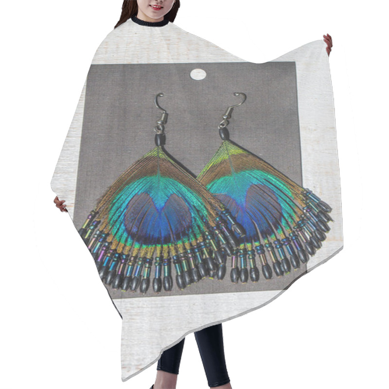 Personality  Peacock Feather Earrings On White Wooden Background, Close Up. Earrings Made Of Peacock Feathers. Top View Hair Cutting Cape