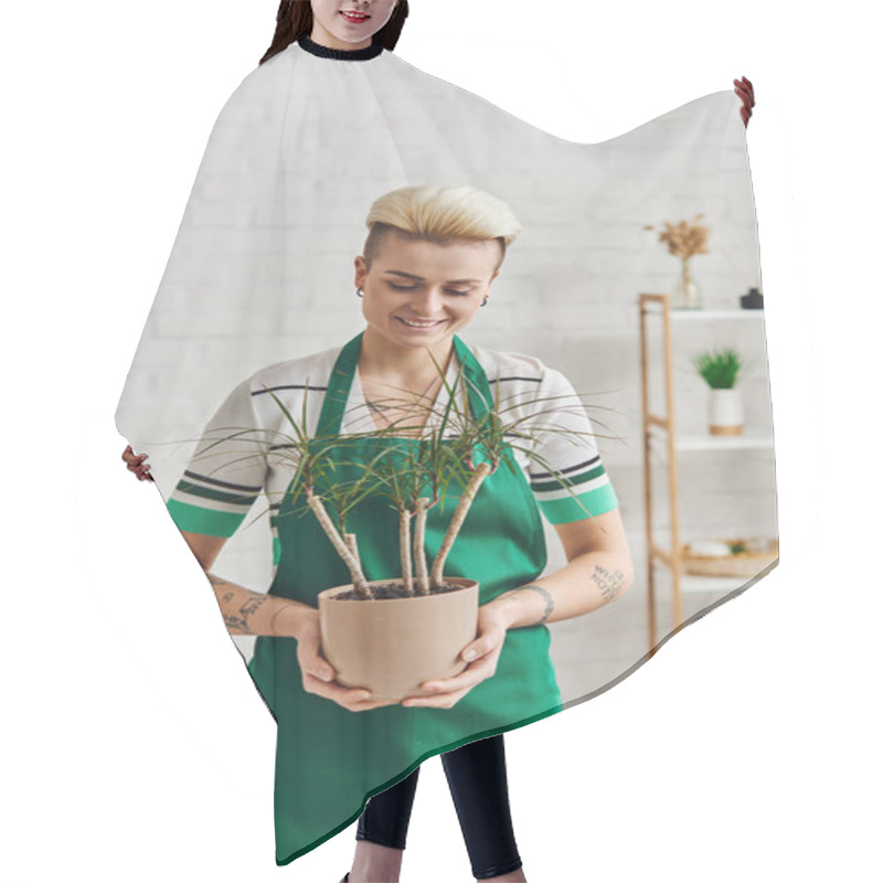 Personality  Overjoyed Tattooed Woman With Trendy Hairstyle Holding Potted Exotic Plant While Standing In Green Apron In Modern Living Room, Plant Therapy, Sustainable Home Decor And Green Living Concept Hair Cutting Cape