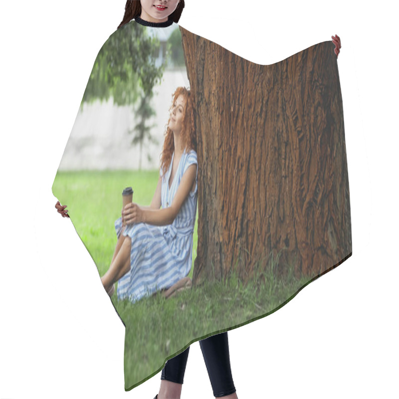 Personality  Full Length Of Pleased Redhead Woman In Dress Sitting Under Tree Trunk And Holding Paper Cup  Hair Cutting Cape