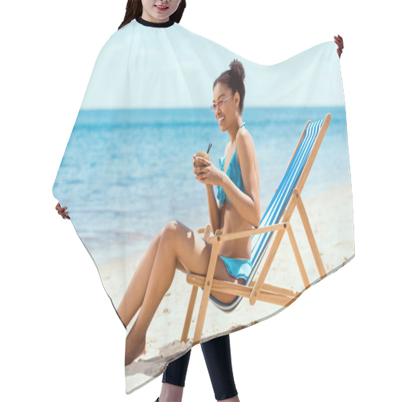 Personality  Happy African American Woman In Bikini And Sunglasses Drinking Cocktail In Coconut Shell While Sitting On Deck Chair On Sandy Beach Hair Cutting Cape