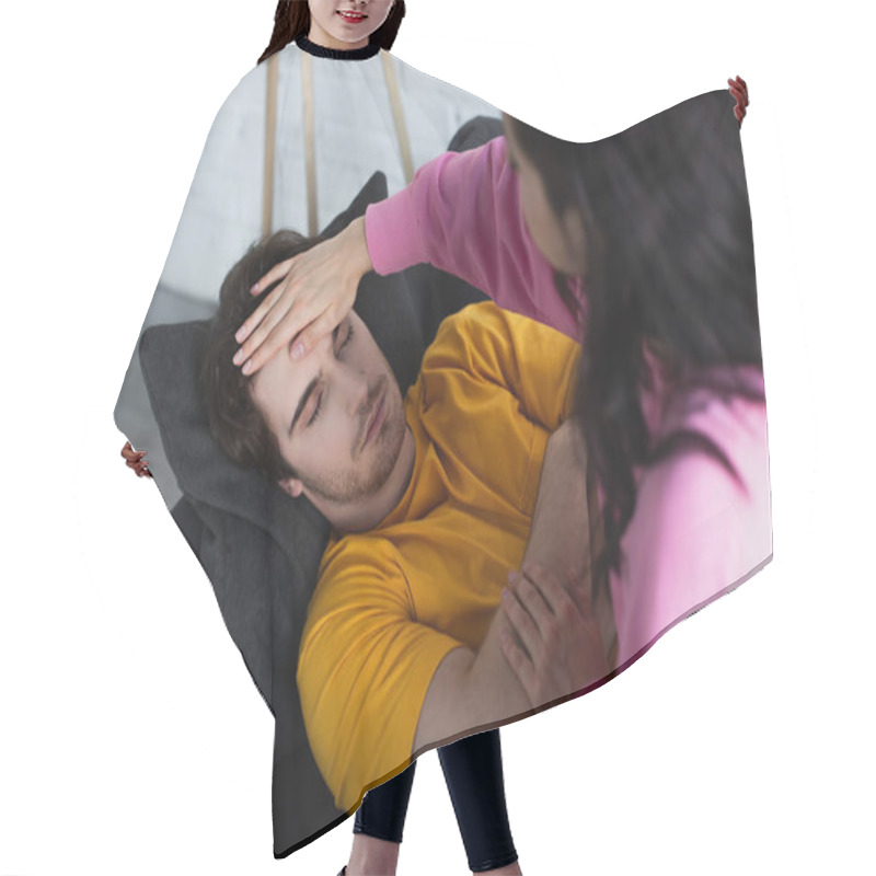 Personality  Young Woman Measuring Temperature With Palm On Forehead Of Sick Young Man Lying On Couch With Closed Eyes At Home Hair Cutting Cape