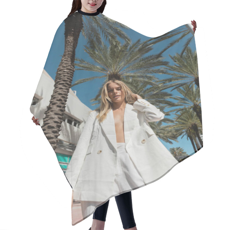 Personality  A Stunning Blonde Woman In A White Suit Stands Gracefully Next To A Vibrant Palm Tree In Miami. Hair Cutting Cape