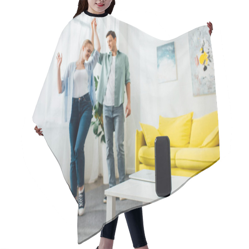 Personality  Selective Focus Of Wireless Speaker And Laptop On Coffee Table And Smiling Man Dancing With Girlfriend At Home Hair Cutting Cape