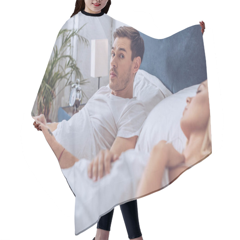 Personality  Man Using Smartphone And Looking At Camera While Lying With Sleeping Wife In Bed Hair Cutting Cape