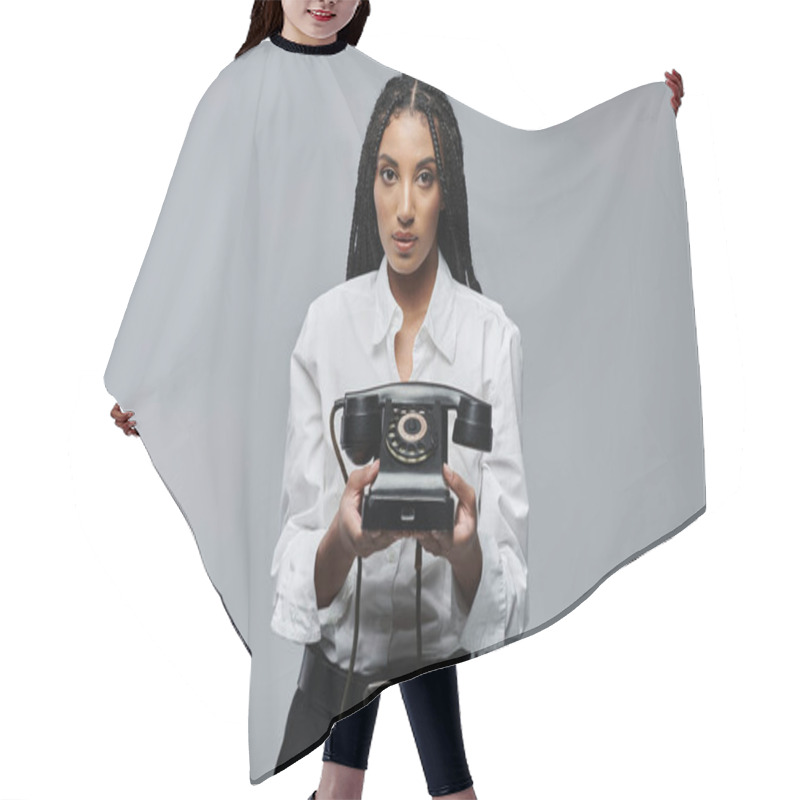 Personality  A Young Woman In A White Shirt Holds An Old Rotary Phone, Posing Against A Gray Backdrop. Hair Cutting Cape