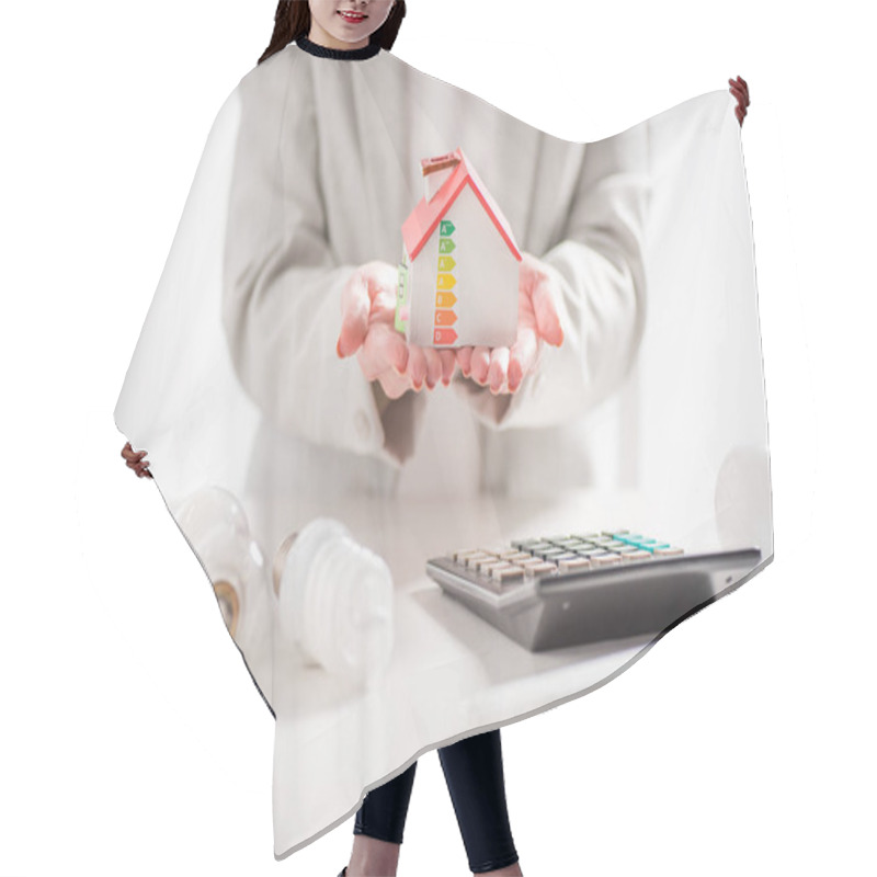 Personality  Cropped View Of Woman Holding Carton House Near Calculator And Light Bulbs On White Background, Energy Efficiency At Home Concept Hair Cutting Cape