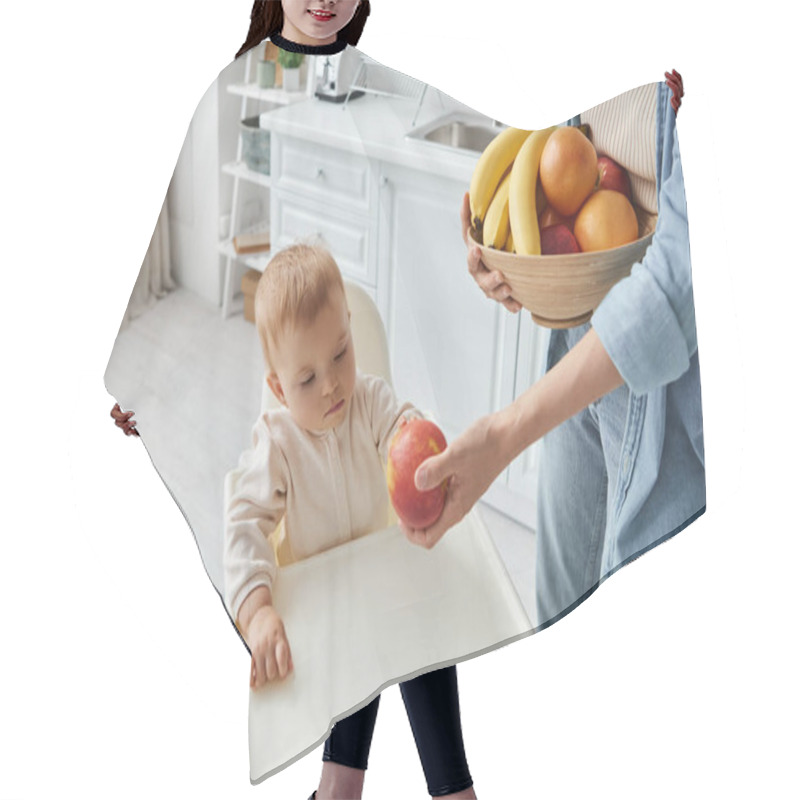 Personality  Mother With Bowl Of Fresh Fruits Proposing Ripe Apple To Little Daughter Sitting In Baby Chair Hair Cutting Cape