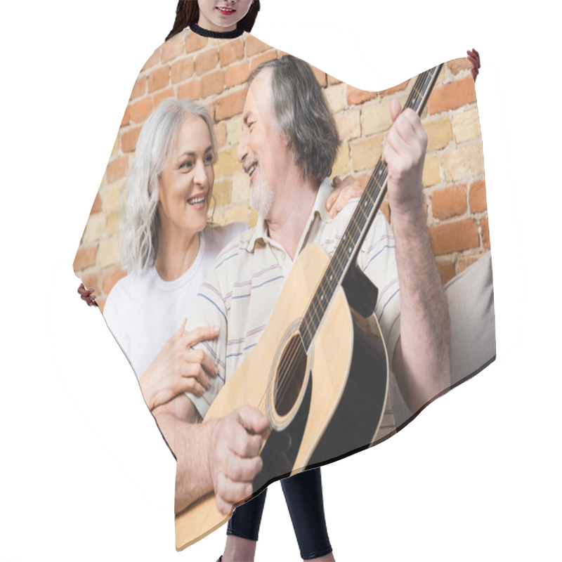 Personality  Happy And Mature Man Playing Acoustic Guitar Near Cheerful Wife  Hair Cutting Cape