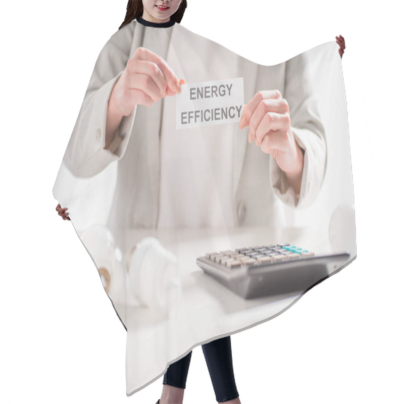 Personality  Cropped View Of Woman Holding Paper Card With Lettering Near Lamps And Calculator On White Background, Energy Efficiency Concept Hair Cutting Cape