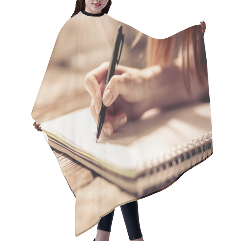 Personality  Close Up View Of Womans Hand Writing With Pen On Notebook On Wooden Table. Hair Cutting Cape