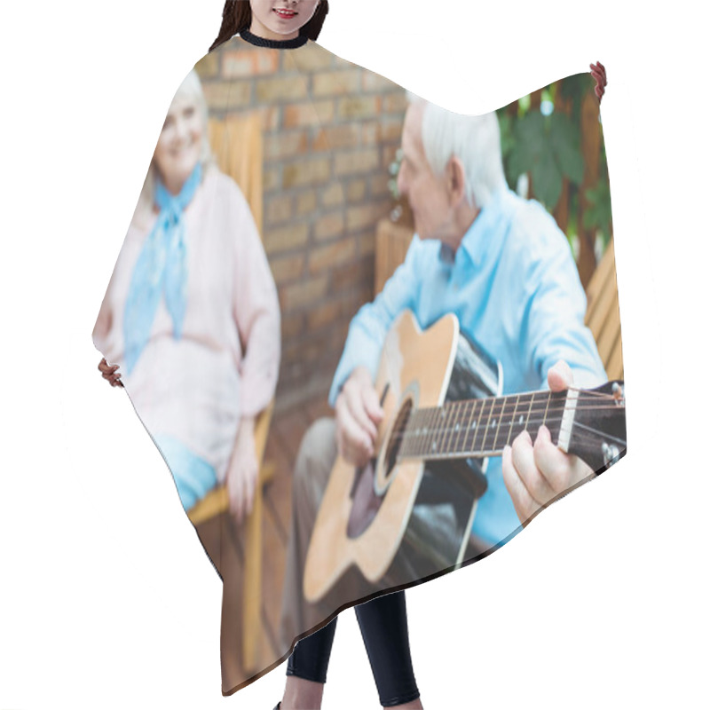 Personality  Selective Focus Of Retired Husband Playing Acoustic Guitar Near Wife  Hair Cutting Cape