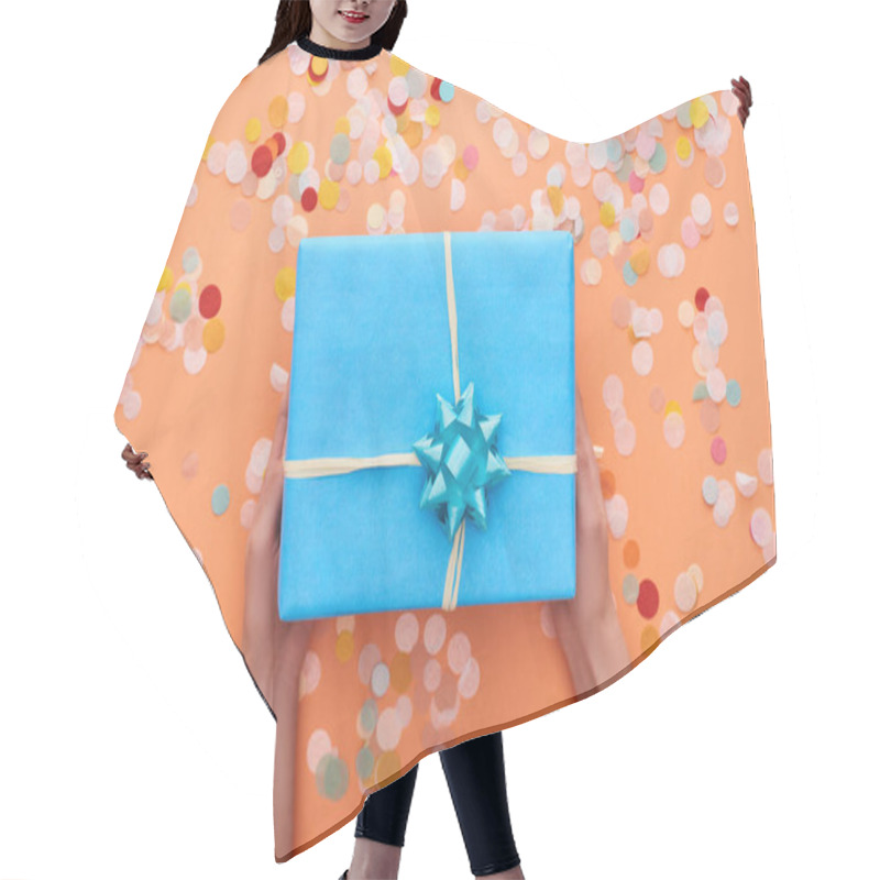 Personality  Cropped View Of Woman Holding Blue Present With Bow Near Confetti On Orange  Hair Cutting Cape