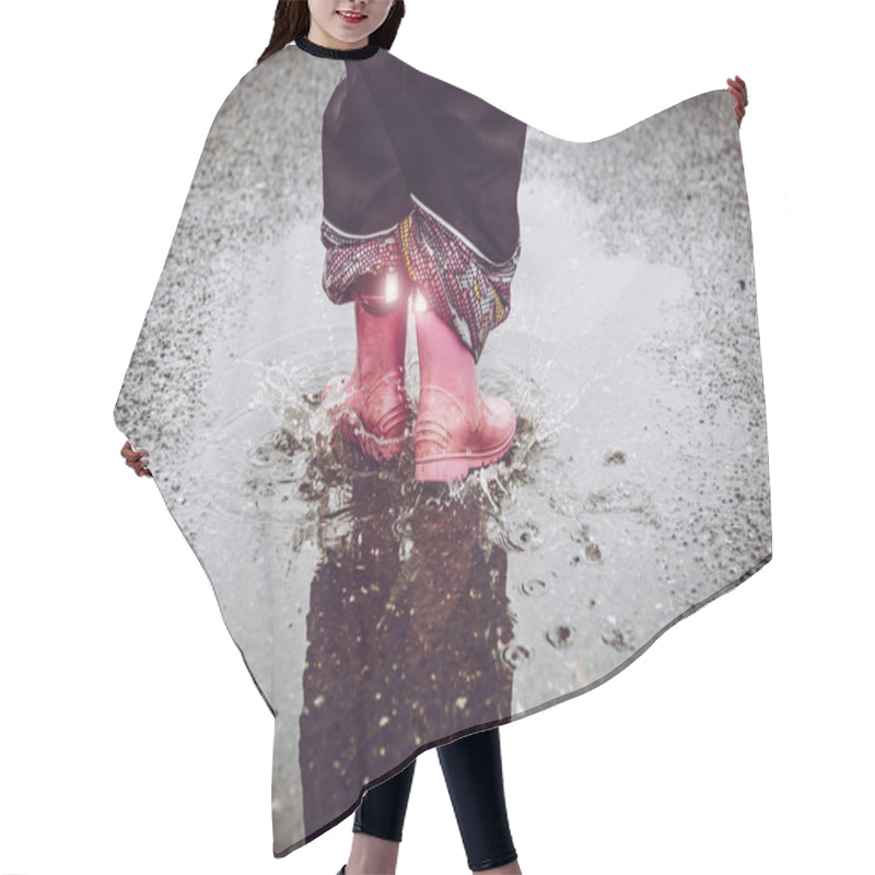 Personality  Girl Having Fun, Jumping In Water Puddle On Wet Street, Wearing Rain Boots With Reflective Detail Fabric Stripes Shining. High Visibility And Safety In Dark Concept. Hair Cutting Cape