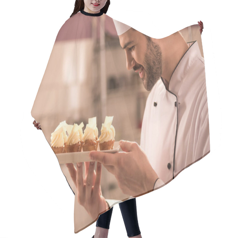 Personality  Side View Of Smiling Confectioner Looking At Cupcakes On Plate In Hands Hair Cutting Cape