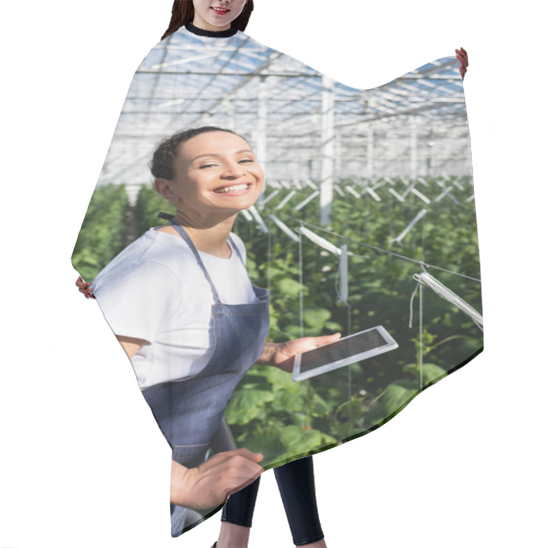 Personality  Excited African American Farmer With Digital Tablet Smiling At Camera In Glasshouse Hair Cutting Cape