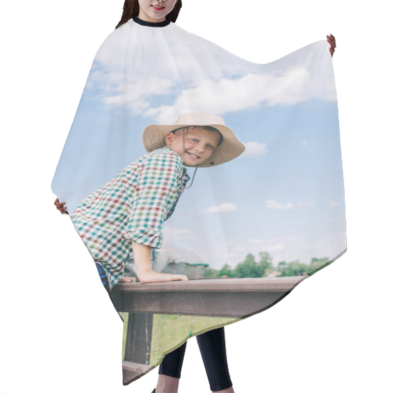 Personality  Cheerful Child In Panama Hat Climbing On Fence And Smiling At Camera On Farm Hair Cutting Cape