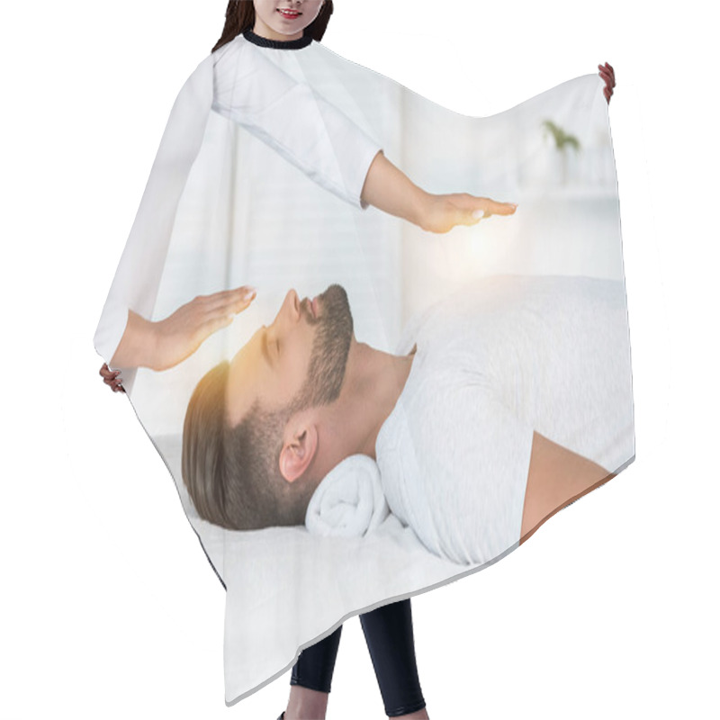 Personality  Cropped View Of Healer Putting Hands Above Head While Healing Handsome Man On Massage Table Hair Cutting Cape