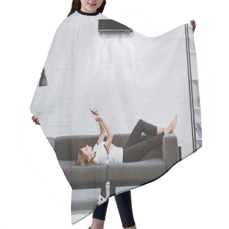 Personality  Relaxed Young Woman Using Smartphone On Couch Under Air Conditioner Hanging On Wall Hair Cutting Cape