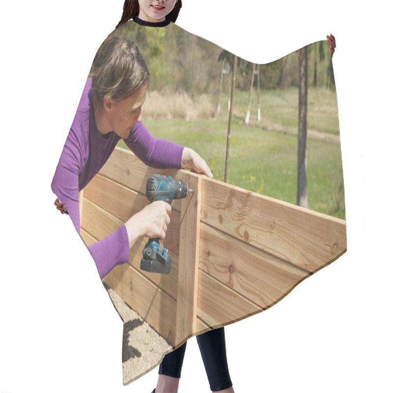 Personality  Woman Building A Wooden Frame For A Raised Garden Bed Using Power Drill. DIY Concept. Powerful Woman. Hair Cutting Cape