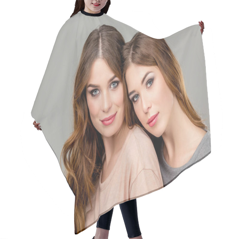 Personality  Portrait Of Attractive Twin Sisters Looking At Camera Isolated On Grey Hair Cutting Cape