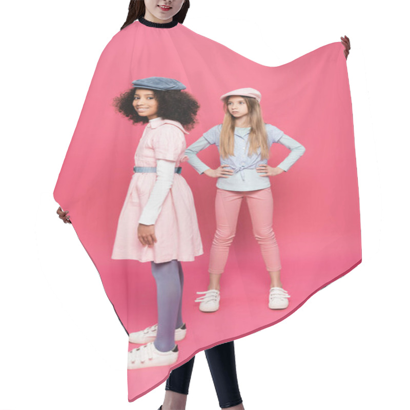 Personality  Stylish Girl Posing With Hands On Hips Near Happy African American Girl Looking At Camera On Pink Hair Cutting Cape