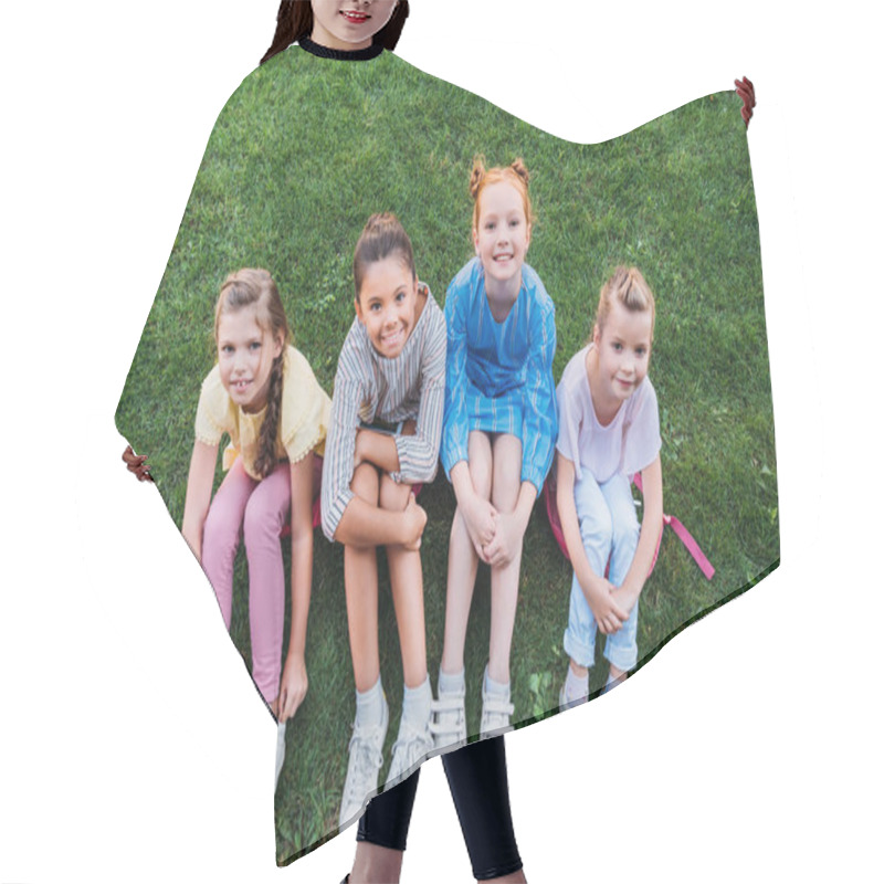 Personality  High Angle View Of Group Of Happy Schoolgirls Sitting On Green Grass Together And Looking At Camera Hair Cutting Cape