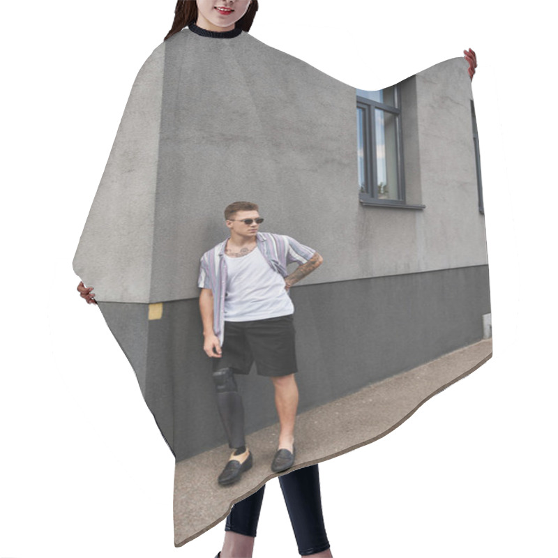 Personality  Young Man With Prosthetic Leg Stands Stylishly Against A Gray Building Wall. Hair Cutting Cape