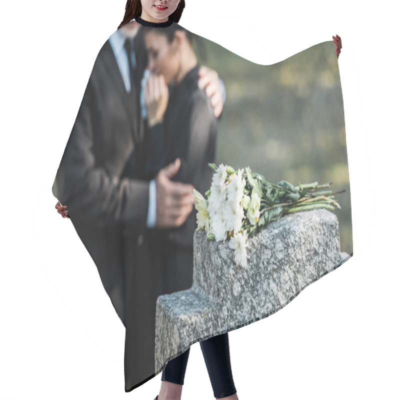 Personality  Selective Focus Of Bouquet On Tombstone Near Man Hugging Woman  Hair Cutting Cape